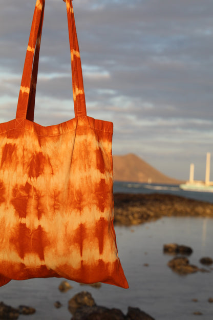 Tie-dye tote bag with a scenic background of water and mountains.